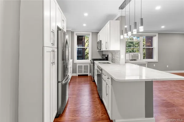 a kitchen with stainless steel appliances kitchen island granite countertop a sink and a refrigerator