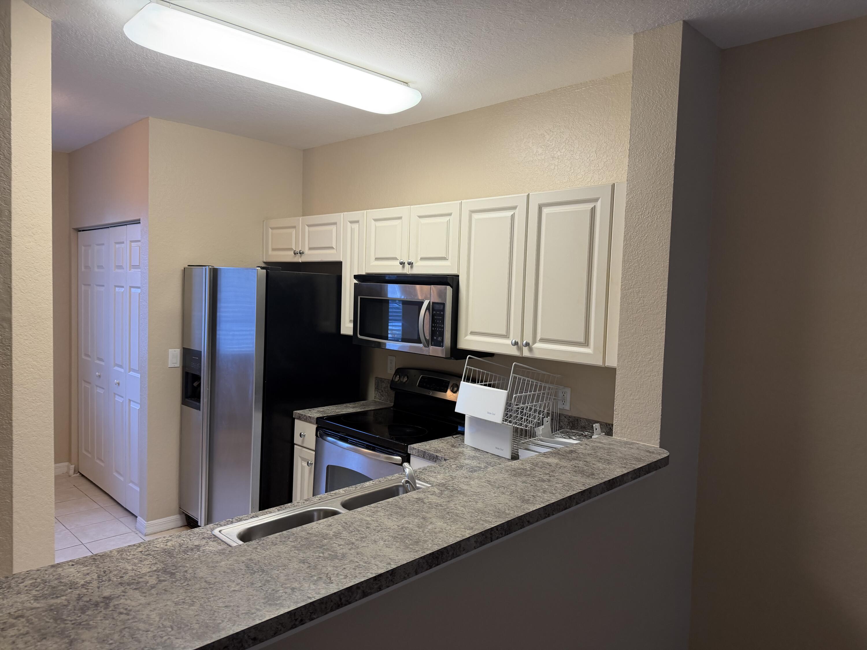 1992 Alamanda Way Riviera Beach, FL 33404 - Photo 13 of 13 a kitchen with stainless steel appliances granite countertop a refrigerator and a sink