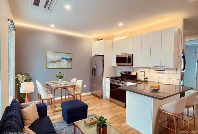 a kitchen with stainless steel appliances granite countertop a stove top oven a sink a dining table and chairs with wooden floor