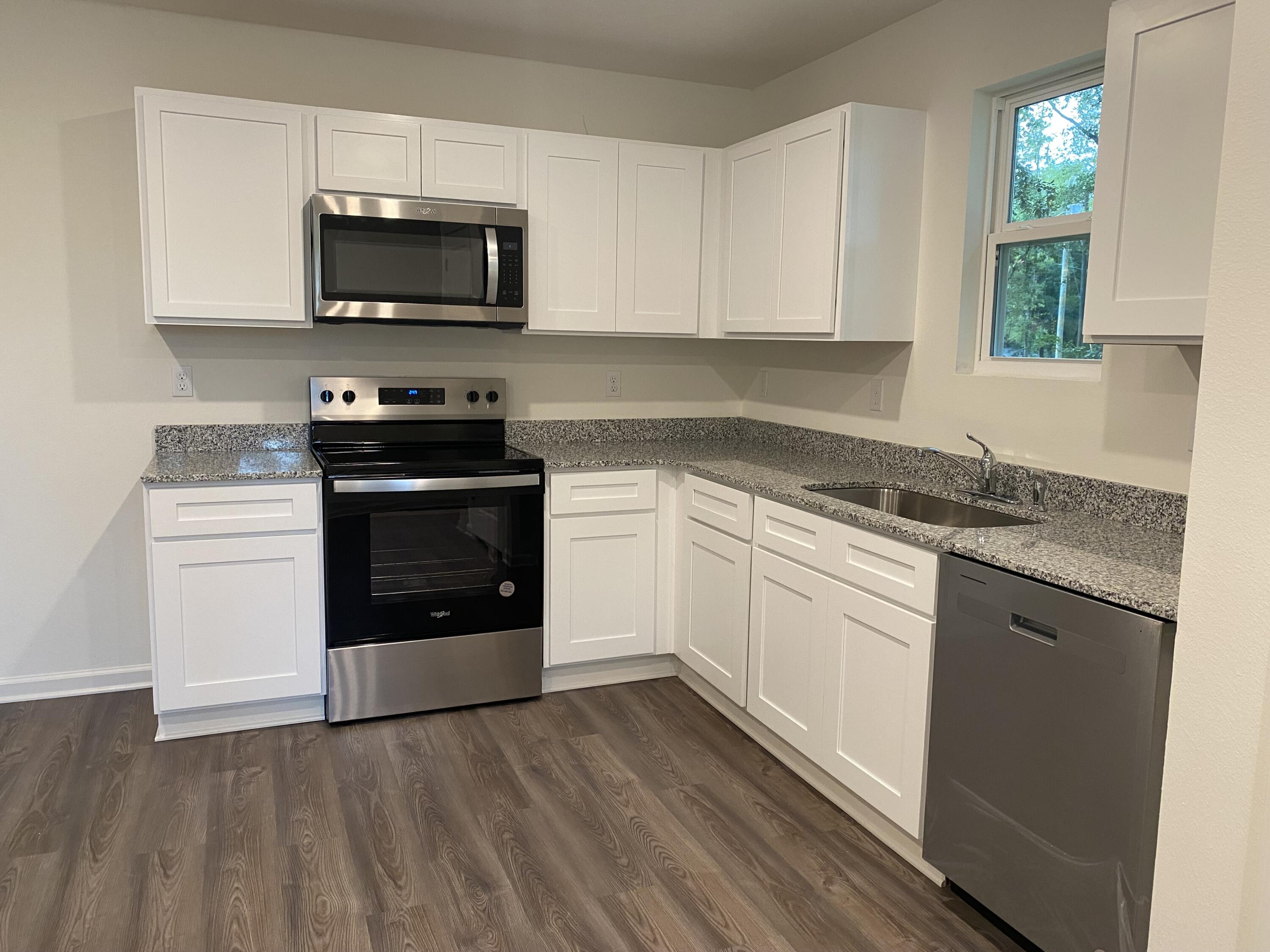 228 Squirrel Road DeFuniak Springs, FL 32433 - Photo 4 of 12 a kitchen with granite countertop a stove top oven microwave and cabinets