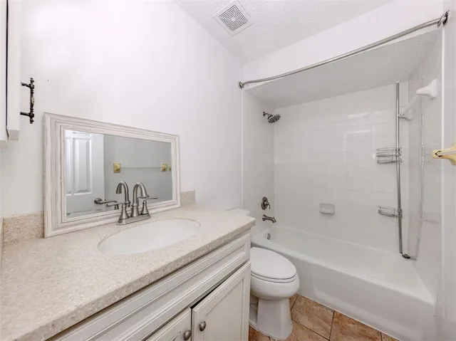a bathroom with a granite countertop sink a toilet and shower