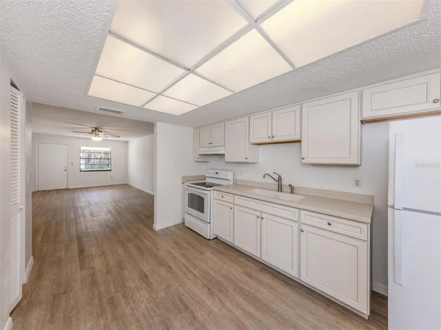 a kitchen with granite countertop a sink cabinets and wooden floor
