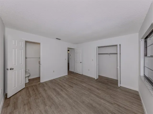 a view of an empty room with wooden floor and closet