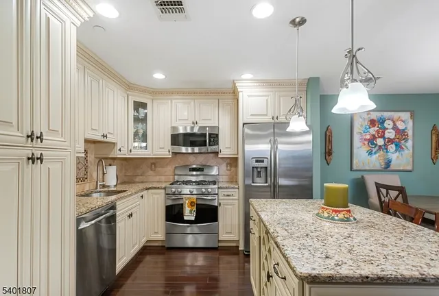 a kitchen with stainless steel appliances granite countertop a sink a stove and a refrigerator