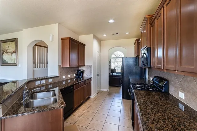 a kitchen with granite countertop stainless steel appliances a sink stove top oven and cabinets