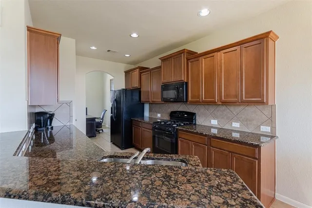 a kitchen with stainless steel appliances granite countertop a sink stove refrigerator and cabinets