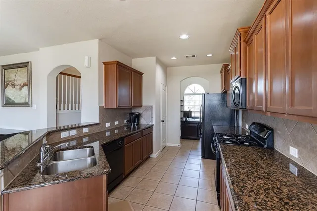 a kitchen with granite countertop stainless steel appliances a sink stove top oven and cabinets
