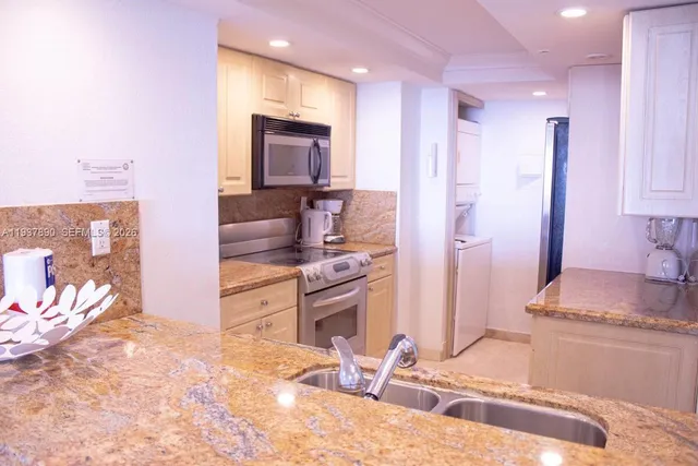 a kitchen with stainless steel appliances kitchen island granite countertop a refrigerator and a sink