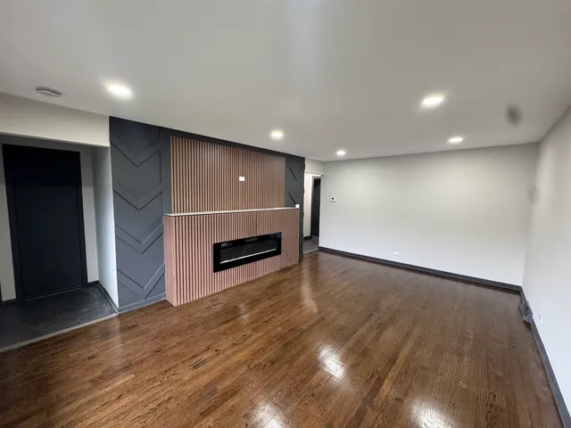 an empty room with wooden floor fireplace and windows