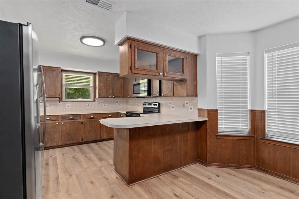 301 East 6th Street Krum, TX 76249 - Photo 2 of 29 Kitchen featuring custom tile backsplash, wood like flooring and plenty of cabinet and counter space.