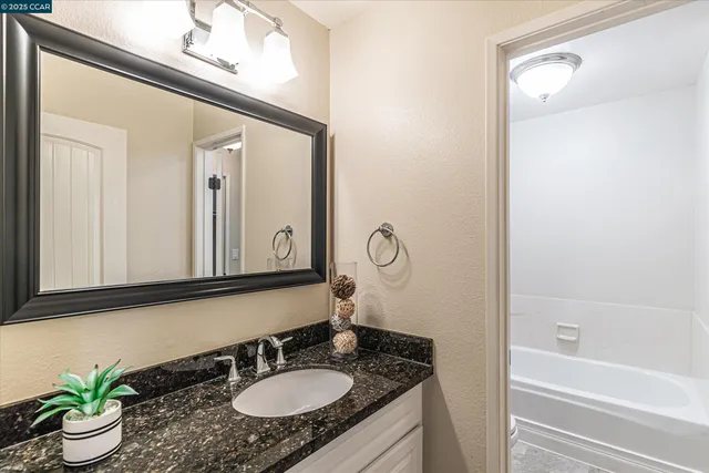 a bathroom with a granite countertop sink and a mirror