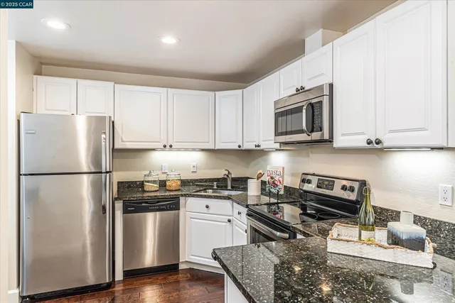 a kitchen with stainless steel appliances granite countertop a refrigerator stove microwave and sink