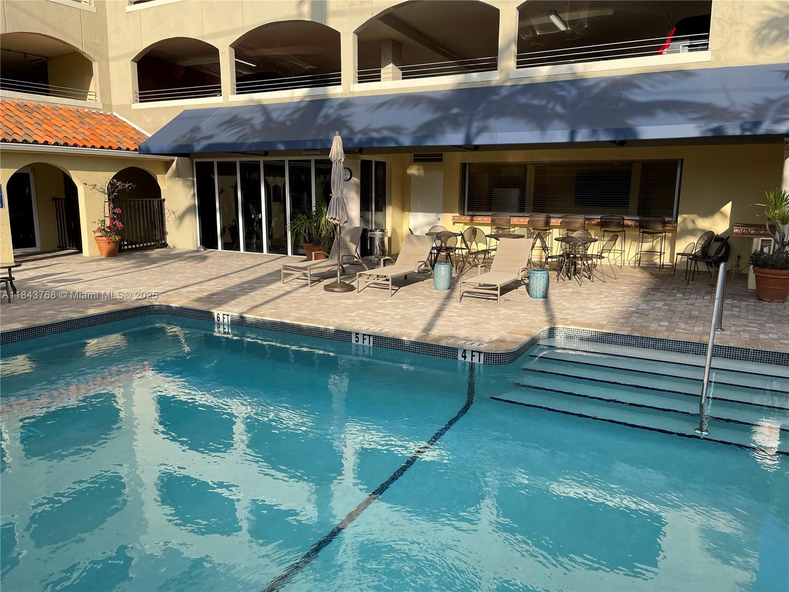 2351 Douglas Road, Unit 1208 Miami, FL 33145 - Photo 16 of 18 a view of a patio with table and chairs near a yard