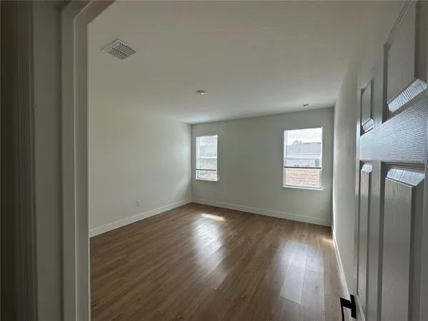 a view of an empty room with wooden floor and a window