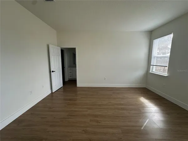 a view of an empty room with wooden floor and a window