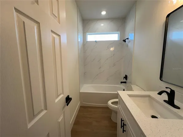 a bathroom with a granite countertop bathtub shower and toilet