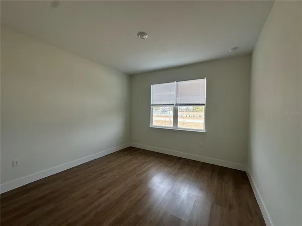 a view of an empty room with wooden floor and closet