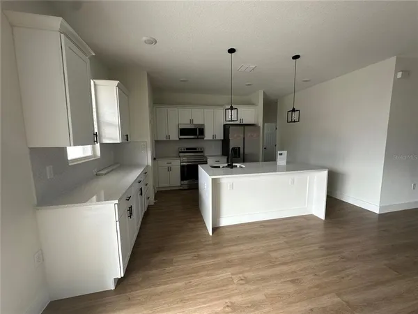 a large kitchen with kitchen island a large counter top space a sink stainless steel appliances and cabinets