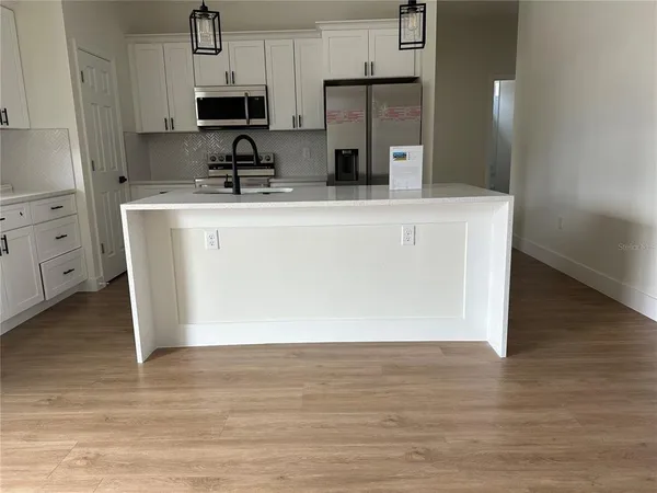 a kitchen with stainless steel appliances a refrigerator a sink a stove a microwave and wooden cabinets