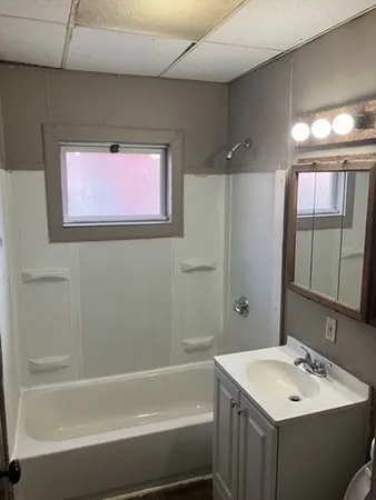 a bathroom with a bathtub sink vanity and mirror