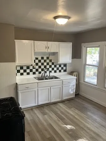 a kitchen with granite countertop white cabinets and window
