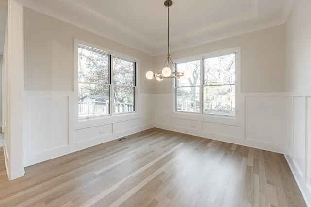 a view of a hallway with a dining room and chandelier fan