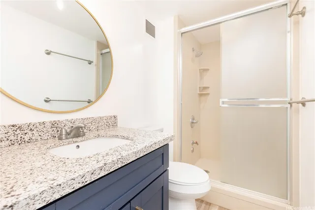 a bathroom with a granite countertop sink a toilet and shower