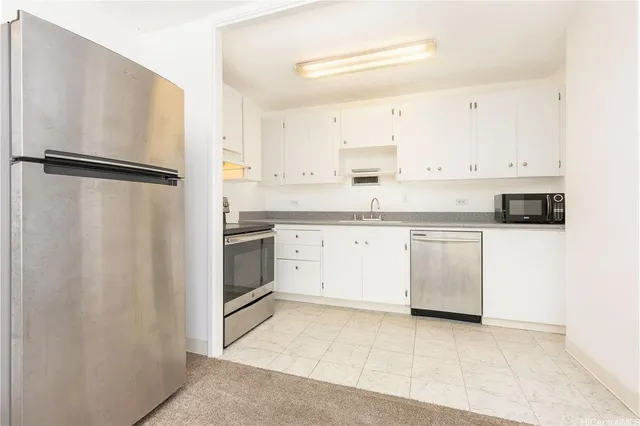 a kitchen with white cabinets stainless steel appliances and a refrigerator