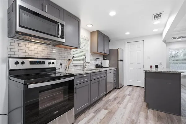 a kitchen with stainless steel appliances kitchen island granite countertop a stove microwave and cabinets