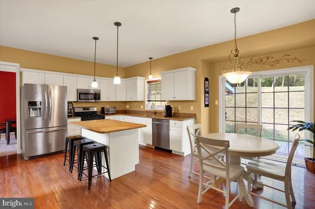 a large kitchen with kitchen island a dining table chairs and a wooden floor