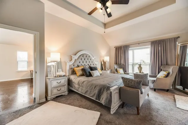 a bedroom with a bed couch and large windows