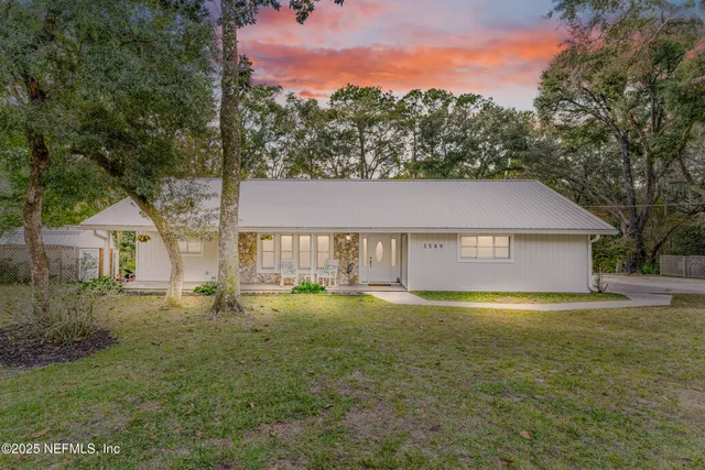 an aerial view of a house with a yard and trees all around