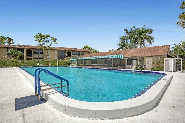 302 Pine Ridge Circle, Unit D2 Greenacres, FL 33463 - Photo 12 of 20 a view of a swimming pool with a garden