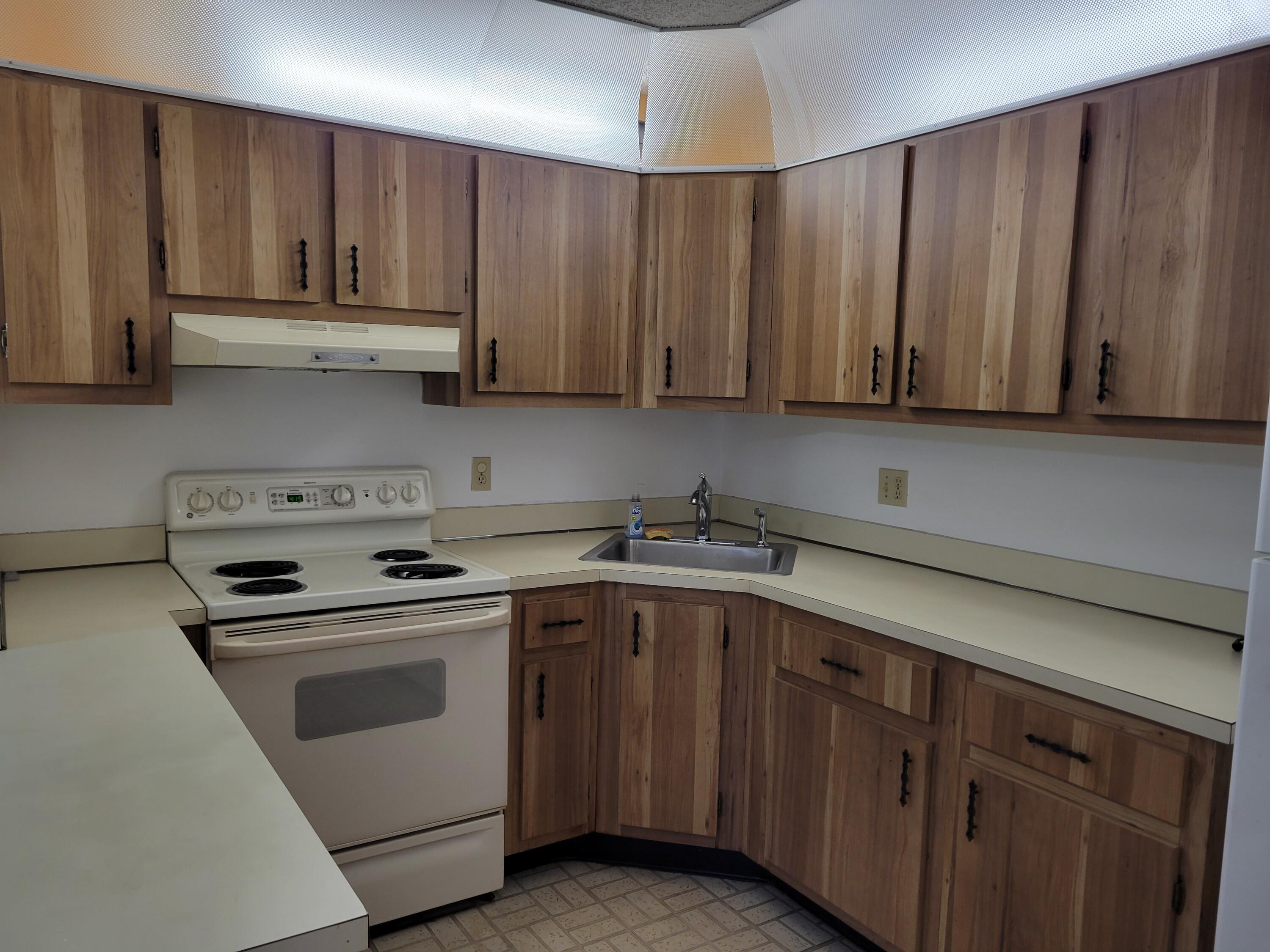 302 Pine Ridge Circle, Unit D2 Greenacres, FL 33463 - Photo 6 of 20 a kitchen with wooden cabinets and a sink