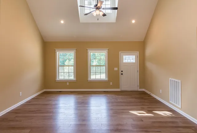an empty room with wooden floor and windows