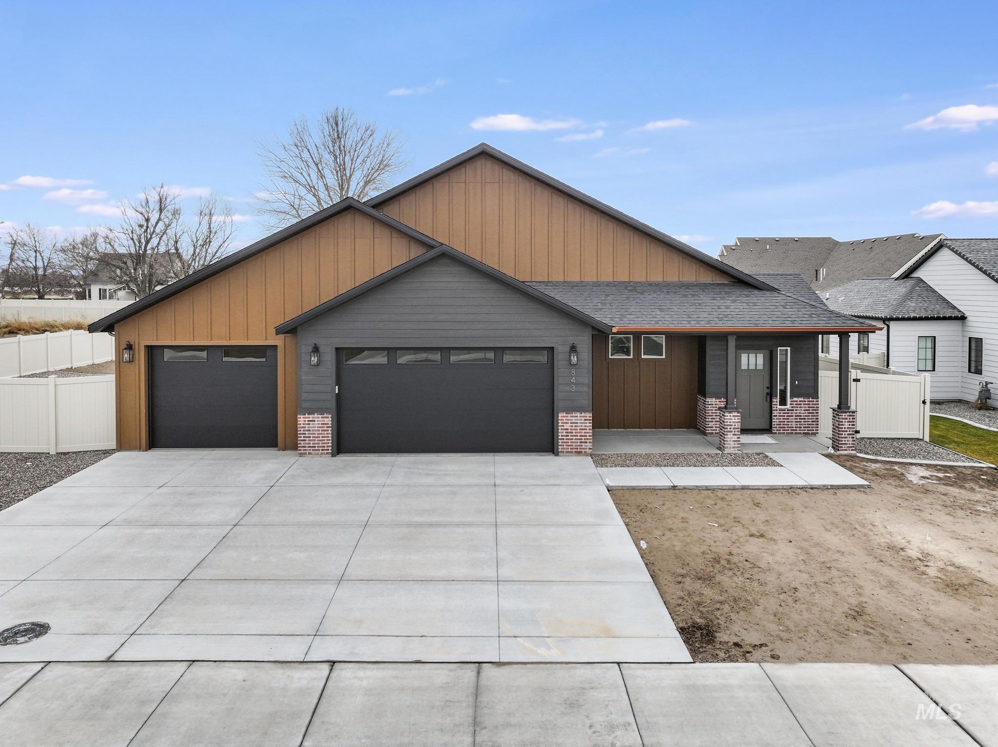 View of front of property featuring driveway, a garage, roof with shingles, and brick siding