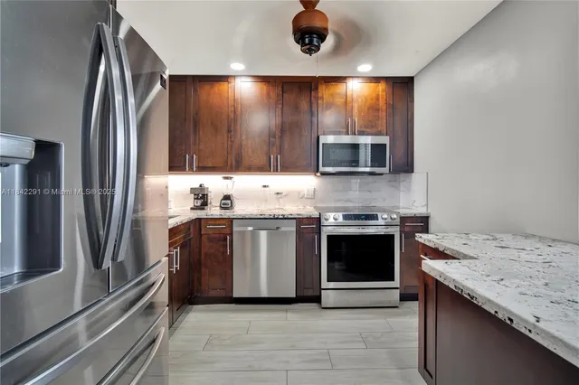 a kitchen with stainless steel appliances kitchen island granite countertop a stove a sink and a microwave