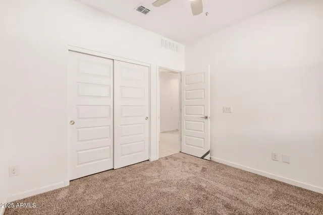 an empty room with a window and a chandelier fan