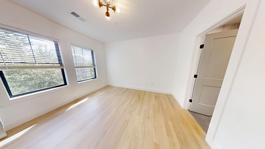 52 Withington Street, Unit 7 Boston, MA 02124 - Photo 6 of 19 an empty room with wooden floor and windows