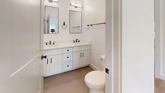 a view of a hallway with wooden floor and a bathroom