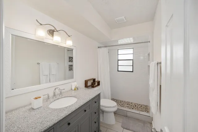a bathroom with a granite countertop double vanity sink mirror and toilet