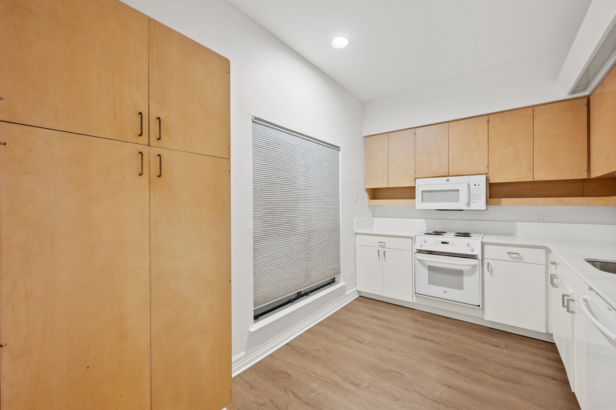 409 East 38th Street, Unit 101 Austin, TX 78705 - Photo 11 of 27 A well-lit kitchen with sleek wooden cabinetry and modern white appliances provides an ideal culinary space. All appliances convey
