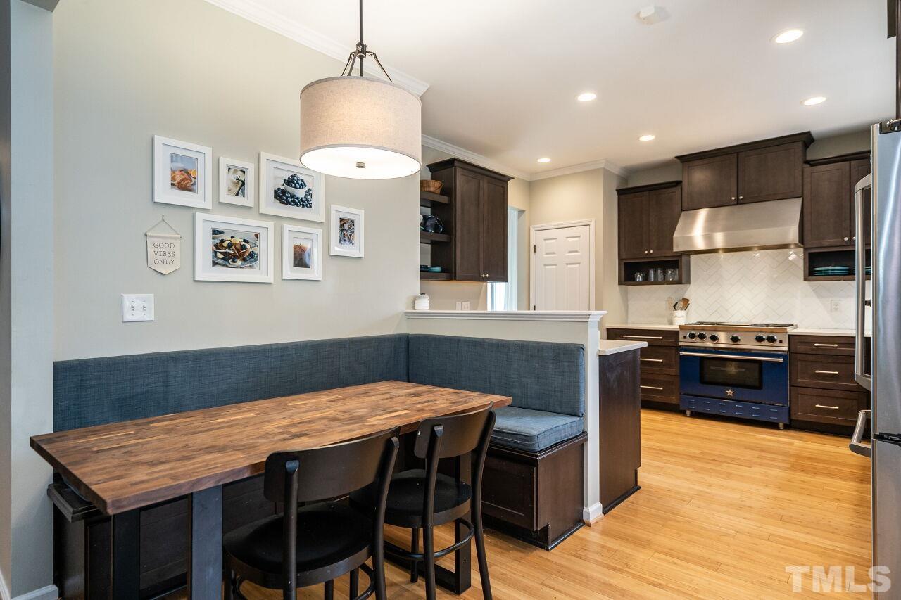 7443 Lagrange Drive Raleigh, NC 27613 - Photo 13 of 28 a kitchen with stainless steel appliances granite countertop a stove top oven a sink a dining table and chairs with wooden floor