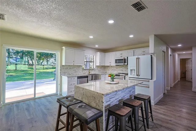 a kitchen with a table chairs refrigerator and wooden floor