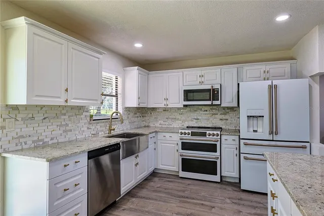 a kitchen with granite countertop white cabinets and stainless steel appliances