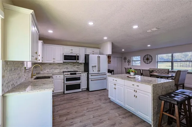 a large kitchen with stainless steel appliances granite countertop a stove and a sink