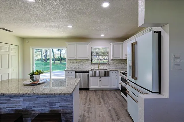 a kitchen with stainless steel appliances granite countertop a refrigerator a stove and a wooden floors