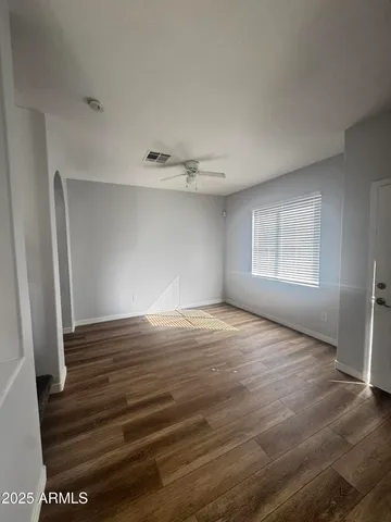 a view of an empty room with wooden floor and a window
