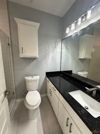 a bathroom with a granite countertop toilet sink and mirror