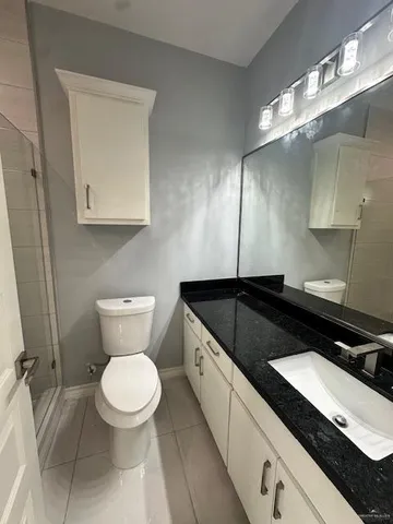 a bathroom with a granite countertop toilet sink and mirror